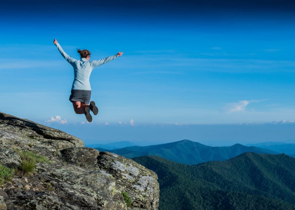 Person springt frei in der Natur – Symbol für wiedergewonnene Belastbarkeit und Bewegungsfreiheit nach Physiotherapie